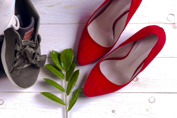 Μεγάλο σωρό από διαφορετικά αθλητικά παπούτσια και τα κόκκινα ψηλοτάκουνα Γυναικεία παπούτσια σε λευκό φόντο. - Φωτογραφία, εικόνα