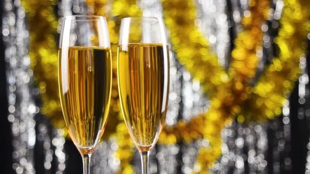 Twee glazen van champagne roterende met Kerstmis zilver en goud klatergoud decoratie op achtergrond. - Video