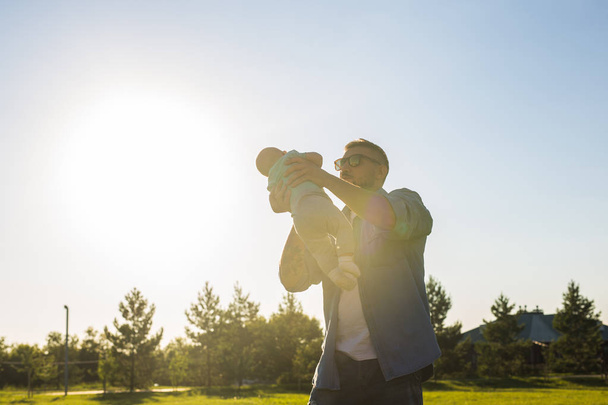 Feliz padre sosteniendo al bebé, lanzando al bebé al aire. Concepto de familia feliz, día del padre y el niño
. - Foto, imagen