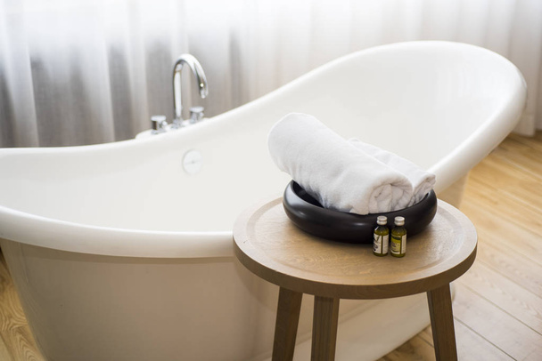 weißes Handtuch und Massagebadeöl auf dem Tisch im Badezimmer. Abstraktes Kurfoto. - Foto, Bild
