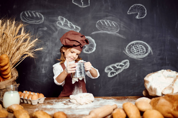 Little girl kneading dough at table - Foto, Bild