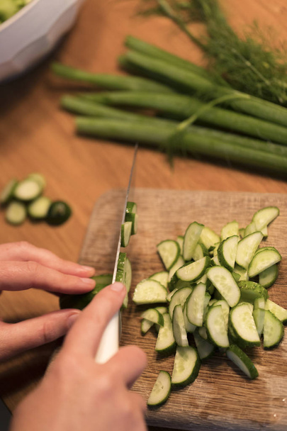Someone cutting a cucumber on a cutting board - Fotografie, Obrázek