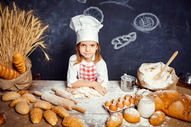 Adorable little girl in chef hat making dough - Фото, изображение