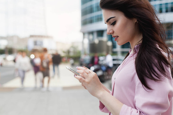 Happy businesswoman using mobile phone near office, beautiful woman browsing phone smiling walking outdoors, female manager texting in a messenger app using modern smartphone  - Photo, image