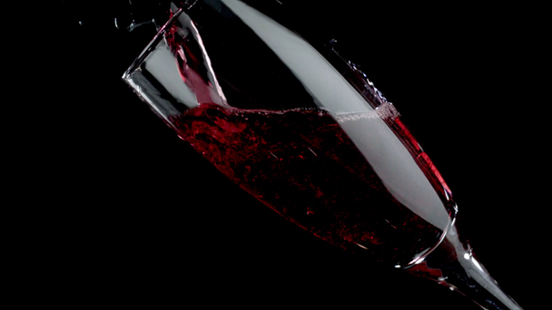 Vino rosso versato in un bicchiere di fondo nero. Rallentatore
 - Filmati, video