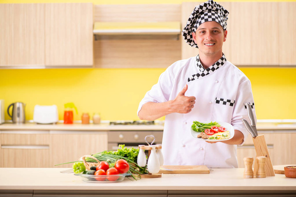 Joven cocinero profesional preparando ensalada en la cocina - Foto, Imagen