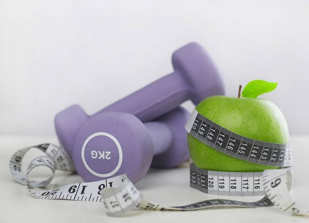 Dumbbells, tape measure and apple - Photo, Image