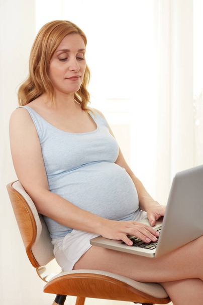 Zwangere vrouw ontspannen met een laptop - Foto, afbeelding