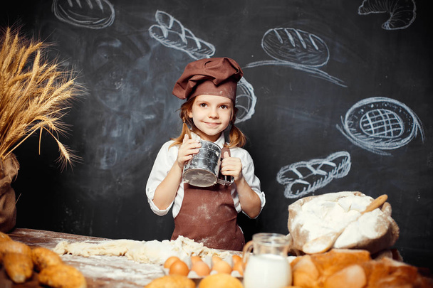 Little girl kneading dough at table - Fotó, kép