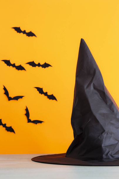 Nietoperze i kapelusz czarownicy z pomarańczowym tle. Koncepcja Halloween. - Zdjęcie, obraz