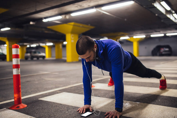 Handsome sportsman doing endurance exercises at the underground parking. - Photo, Image