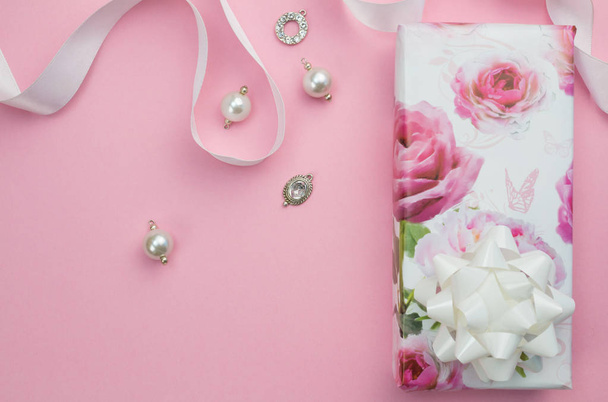 Geschenkverpackung mit Schleife und Charms auf rosa Hintergrund mit Platz für Text - Foto, Bild
