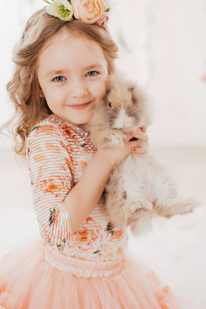 Красива маленька дівчинка з кроликом позує в студії
 - Фото, зображення