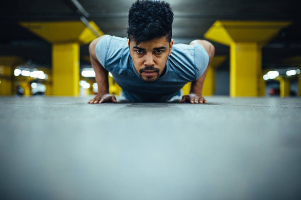 Handsome man doing push ups in an underground parking. - Foto, afbeelding