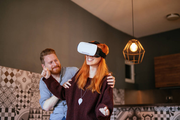 Prise de vue d'amis s'amusant en utilisant un casque de réalité virtuelle dans l'appartement
. - Photo, image
