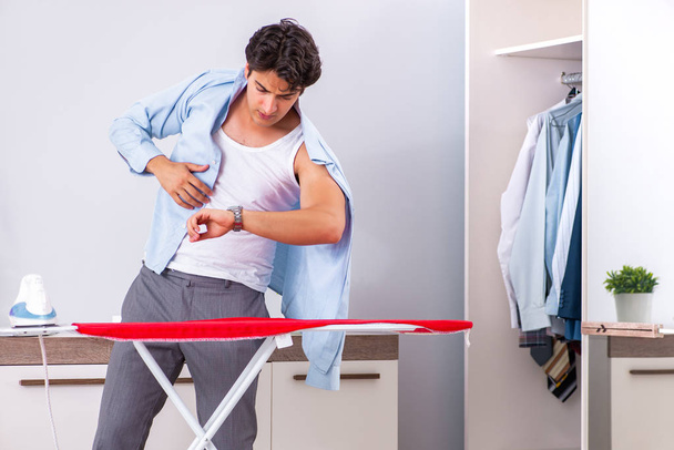 Young man ironing in the bedroom  - Fotó, kép