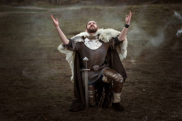 Cavaleiro de armadura ajoelhado e orar levantou a cabeça para o céu
. - Foto, Imagem