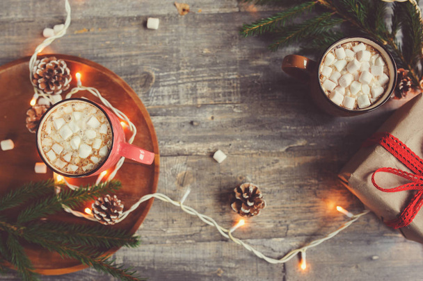 top view of hot cocoa with marshmallows on rustic wooden table with christmas lights. Cozy winter home concept - Foto, Imagen
