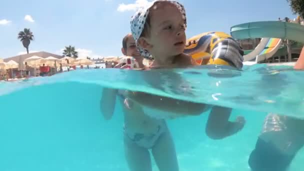 Imágenes submarinas de cámara lenta del niño nadando con anillo inflable en la piscina en un día soleado
 - Imágenes, Vídeo