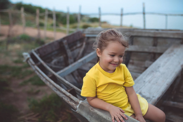Retrato de una chica tímida sentada en un viejo barco en una noche de verano
 - Foto, Imagen
