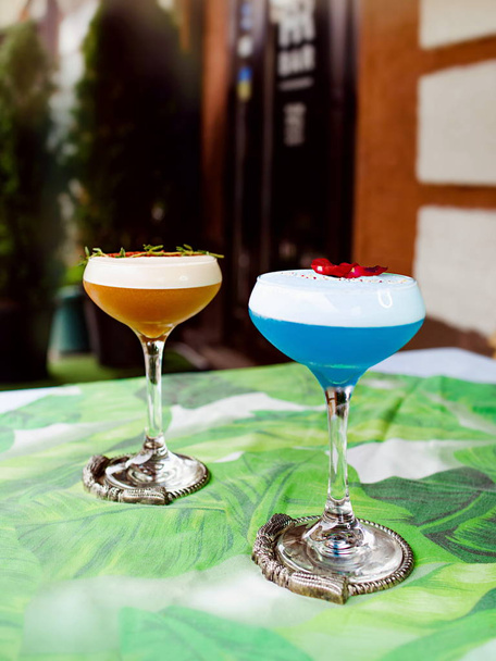 Blue curacao and beidge cocktails standing on the table outdoor - Фото, изображение