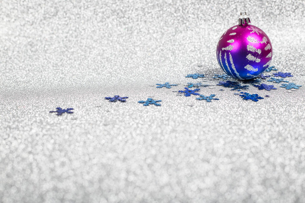 Christmas holiday composition of festive decor ball and snowflakes on silver glitter bokeh background - 写真・画像