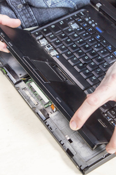 Az ember leszereli a laptop burkolat elektronikus berendezések szolgálatában. - Fotó, kép