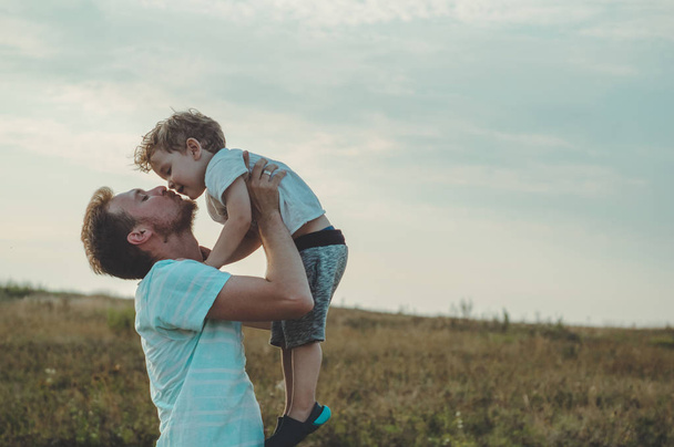Father throws up his cute and little son in the fresh air. Father's Day, Father and his son baby boy playing and hugging outdoors. - Foto, Imagem