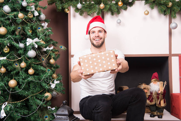 Happy man give present box at christmas tree and fireplace - Zdjęcie, obraz