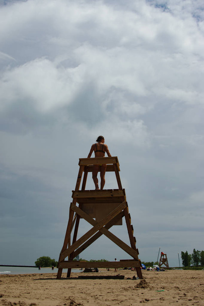 Mujer escalando la torre de guardia de la vida en la playa
 - Foto, Imagen