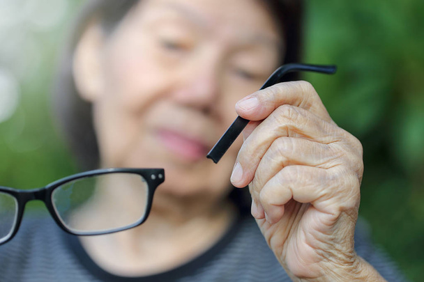 Starsza kobieta azjatyckich naprawić złamane okulary - Zdjęcie, obraz