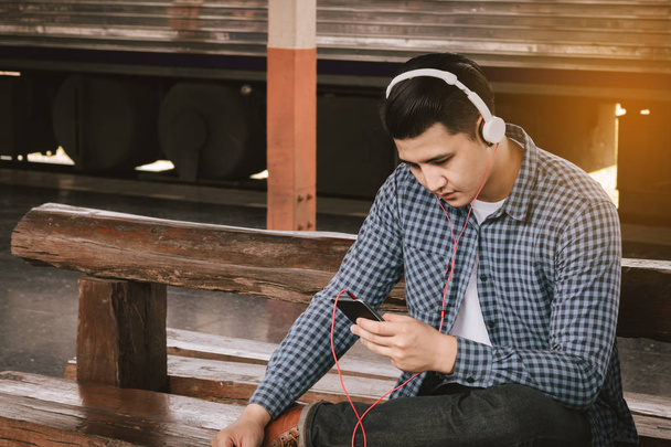 Hipster asiático hombre escuchar música en tren estación
. - Foto, Imagen