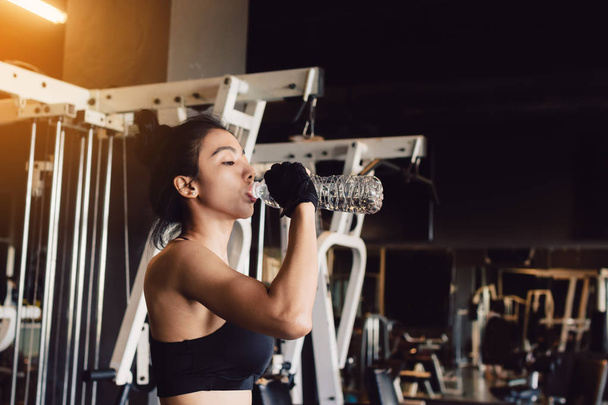 Azjatki, młoda kobieta wody pitnej w siłowni. - Zdjęcie, obraz