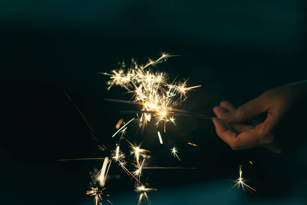 Female hands holding sparkler with night background - Фото, изображение