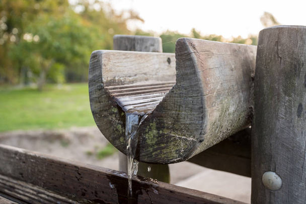in a park there is a wooden waterfall with a water pump - Photo, Image