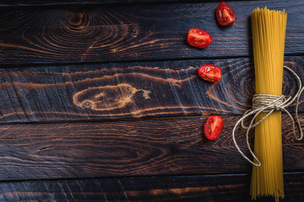 イタリアの生パスタ スパゲッティとダークウッドのテーブルの上にトマトを表示します。 - 写真・画像