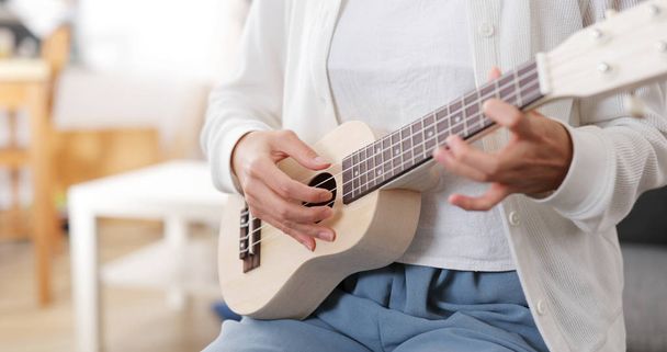 Woman play a song on ukulele at home - Photo, Image