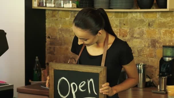 Pracownik kawiarni posiada otwarty znak i spogląda na klienta. - Materiał filmowy, wideo