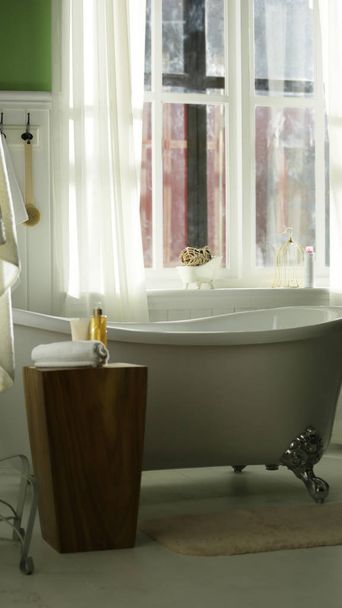 eine weiße Badewanne in der Nähe des Fensters zum Entspannen im Sonnenlicht - Foto, Bild