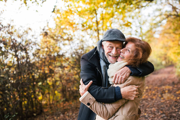 Senior couple standing in an autumn nature, hugging. - Foto, afbeelding