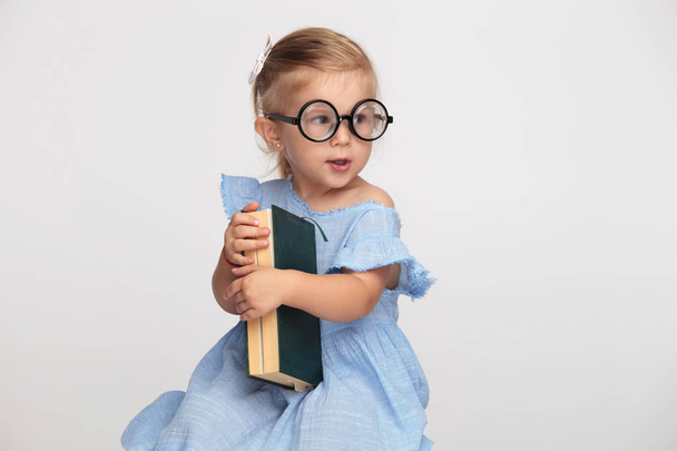 legal nerd menina segurando seu livro e espera para a escola para começar no fundo cinza
 - Foto, Imagem