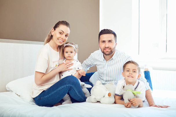 Portrait of happy family on bed in bedroom - Photo, Image