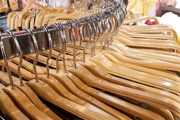 Detail der Kleidung, die an Holzbügeln in einem Modegeschäft hängt. - Foto, Bild