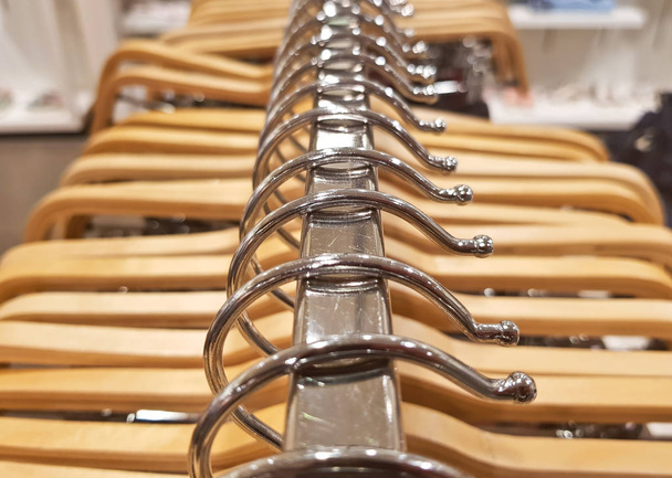 detail van kleren opknoping op houten hangers in een mode-winkel. - Foto, afbeelding