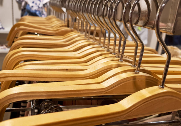 Détail des vêtements suspendus aux cintres en bois dans un magasin de mode
. - Photo, image