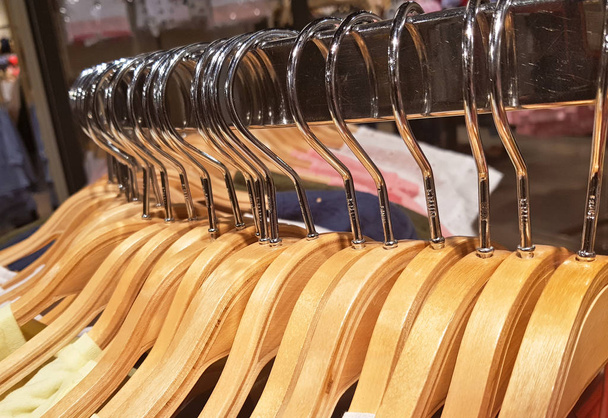 detal ubrania wiszące na drewniane wieszaki w sklep odzieżowy. - Zdjęcie, obraz