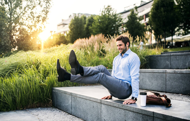 A happy businessman outdoors on stairs at sunset., handstand in L-sit position. - 写真・画像