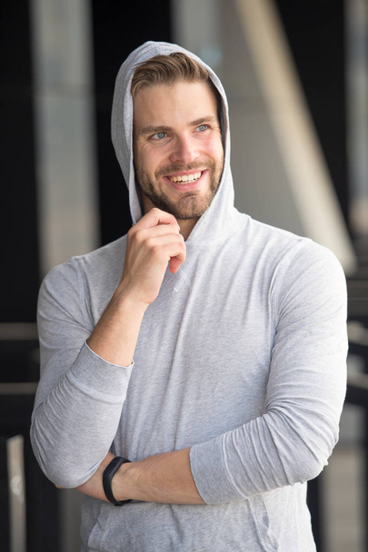 Dream future achievement. Guy bearded attractive casual clothes hooded. Man with bristle smiling dreamy face urban background defocused. Man unshaven guy looks handsome hooded. Dream about success - Photo, image