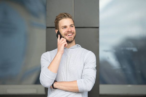 Man with beard call smartphone urban background. Guy happy smile use smartphone to communicate friends. Man use mobile phone call friend. Pleasant conversation concept. Glad to hear you - Фото, зображення