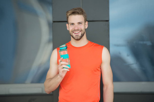 Sporty accessory. Man athlete hold special sporty bottle care hydration body after workout. Refreshing vitamin drink. Athlete drink water after training. Man athletic appearance holds water bottle - Photo, image